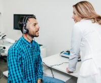 Мужчина на приеме у врача проходит проверку слуха